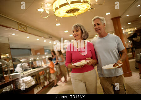 Due adulti che trasportano le piastre del cibo in un ristorante a buffet. Foto Stock