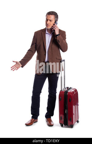 Imprenditore lamenta sul telefono circa un cancellato il volo della compagnia aerea o chiamare per un tardo rideshare trasporto. Egli è in attesa con i bagagli come se Foto Stock