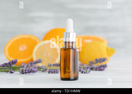 Bottiglia con naturale di agrumi arancio, limone e l'olio essenziale di lavanda su sfondo di legno. Foto Stock