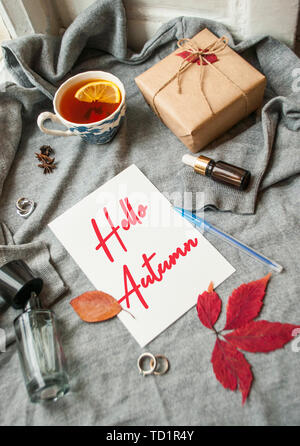 Tazza di tè con limone, giftbox e diversi accessori sulla maglia grigio Sfondo . Accogliente autunno-inverno concetto. Foto Stock