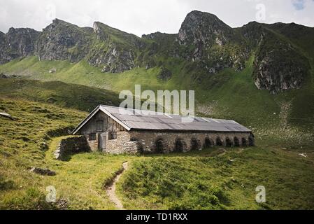 Una casa in caduta su di una collina tra le montagne. Foto Stock