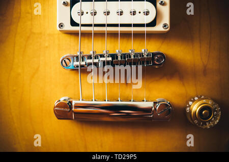 Dettagli della chitarra elettrica, pickups, bridge e stringhe di montaggio sul corpo sunburst, close-up. Foto Stock