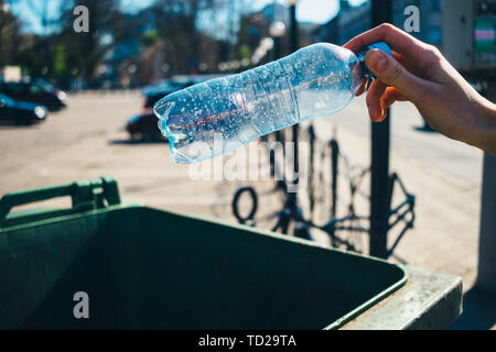 Donna di lancio a mano in plastica vuoto bottiglia di acqua nel cestino nella città di close-up. Foto Stock
