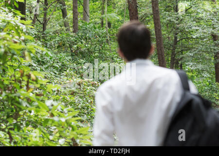 Giovane uomo è sempre lontano dalla zona urbana di andare hicking nella foresta Foto Stock