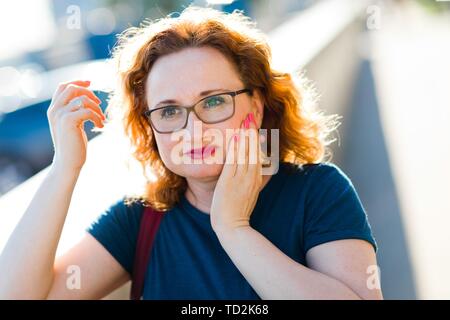 Donna attraente sulla sensazione di strada improvviso mal di denti - disagio gesto Foto Stock