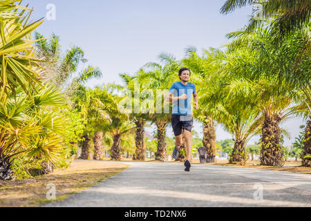 Runner atleta che corre al Tropical Park. uomo sunrise fitness jogging allenamento il concetto di benessere Foto Stock