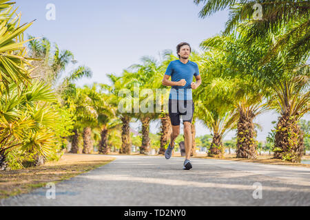 Runner atleta che corre al Tropical Park. uomo sunrise fitness jogging allenamento il concetto di benessere Foto Stock