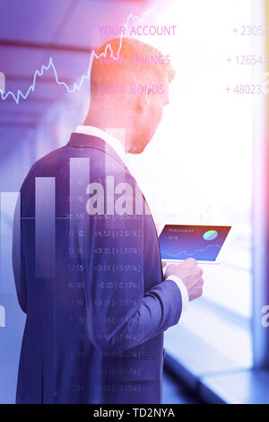 Giovane uomo che controlla il suo portafoglio di investimenti sul suo computer tablet, online trading concetto, doppia esposizione Foto Stock