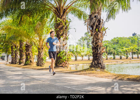 Runner atleta che corre al Tropical Park. uomo sunrise fitness jogging allenamento il concetto di benessere Foto Stock