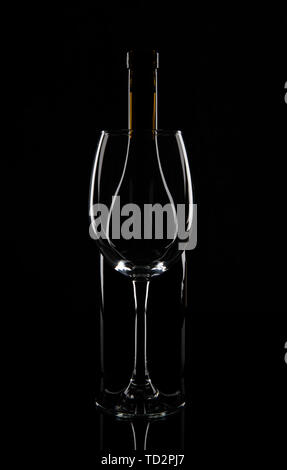 Bottiglia di vino dietro il vetro del vino, isolato su nero Foto Stock