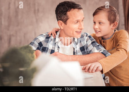 Biondo e figlio indossando maglietta gialla abbraccia il suo padre Foto Stock