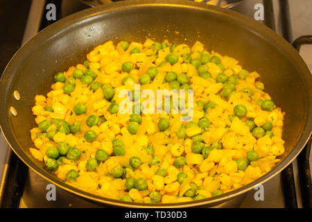 I Piselli di granturco dolce e cipolle fritte in padella su un fornello a gas. Foto Stock