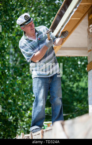 Ritratto di un maschio repairman impegnato nella riparazione di un tetto di una casa, un ritratto contro una piastrella Foto Stock