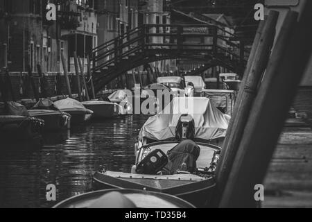 Un colpo di gondola nero e di balena parcheggiato sul Lato di un fiume stretto in Italia Foto Stock