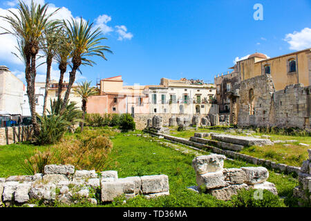 Incredibile rovine del Tempio di Apollo in Isola di Ortigia, Siracusa, Sicilia, Italia. Notevole il Greco antico monumento, sito archeologico. I resti di un tempio. Adiacente palme, giornata di sole e cielo blu. Foto Stock