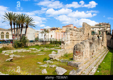 Il Greco antico rovine del Tempio di Apollo in Isola di Ortigia, Siracusa, Sicilia, Italia fotografato con adiacente palme. Colonnato rovine, significativo sito archeologico. Giornata di sole e cielo blu. Foto Stock