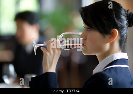 Giovane donna di bere un bicchiere di vino rosso. Foto Stock