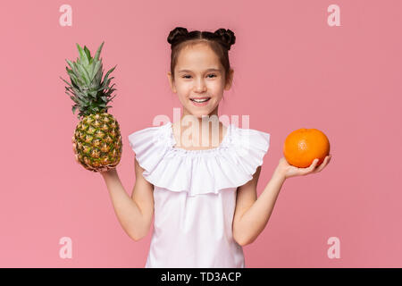 Incantevole piccola ragazza con ananas fresco e arancione Foto Stock