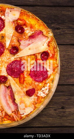 Una deliziosa pizza italiana con salame, pancetta e formaggio parmigiano Foto Stock