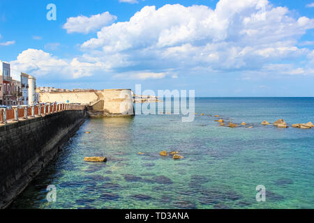La magnifica vista del mare blu e adiacente la costa della città di Siracusa, Sicilia, Italia in una giornata di sole con cielo blu. Pietre in acqua di mare. Fotografato nell'isola di Ortigia. Popolare località turistica. Foto Stock