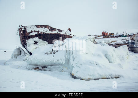 Russia, Olihon island, il lago Baikal, piccola città piccola città, street, fatiscente, veicoli, neve e neve montagne, cartelli stradali, barche, congelate, permafrost, neve e ghiaccio, naufragio Foto Stock
