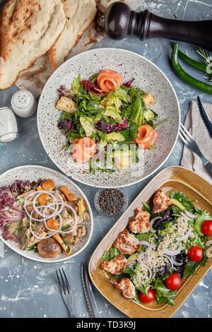 Concetto di cibo, tavolo con vari snack collocato su di esso. Insalata con salmone, Cesare skuric, funghi sott'aceto, pane. Foto Stock