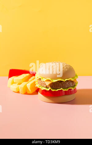 Hamburger di plastica, insalata di pomodoro, la frittura di patate con il giallo. Foto Stock