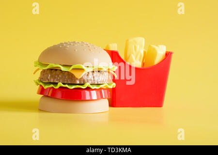 Hamburger di plastica, insalata di pomodoro, la frittura di patate con il giallo. Foto Stock