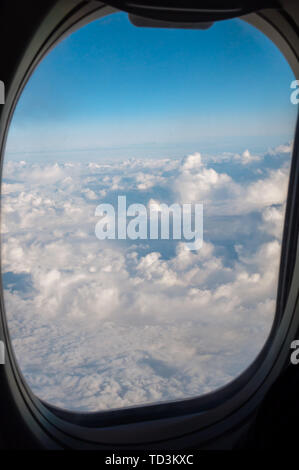 Viaggi di altitudine al di sopra delle nuvole attraverso l'oblò di un aereo Foto Stock