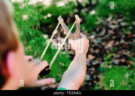 Bambino che gioca con la sua fionda in un parco divertimento in libertà. Foto Stock