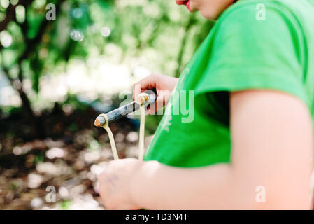 Bambino che gioca con la sua fionda in un parco divertimento in libertà. Foto Stock