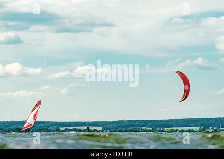 Kitesurfer e Windsurf Vela passato l'altro. Una varietà di attività all'aperto sul concetto di acqua Foto Stock