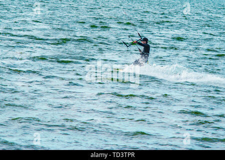 Un kiteboarder viene tirato attraverso l'acqua da un aquilone di potenza Foto Stock