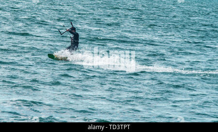 Un kiteboarder viene tirato attraverso l'acqua da un aquilone di potenza Foto Stock