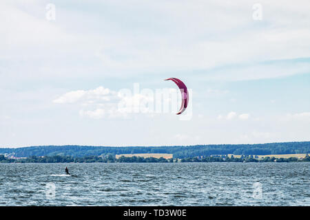 Un kiteboarder viene tirato attraverso l'acqua da un aquilone di potenza Foto Stock