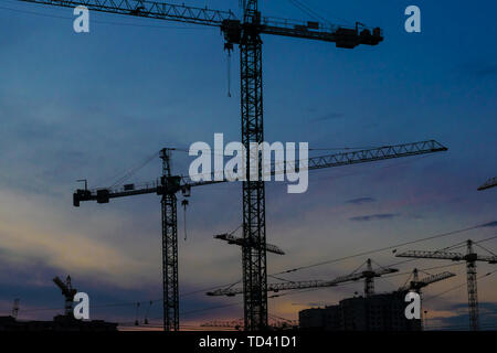 Gruppo di gru per edilizia sviluppando gli edifici con Cielo di tramonto sullo sfondo Foto Stock