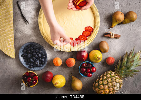 Mani femminili preparare Tart torta con pasta fresca e colorata frutta organica Foto Stock