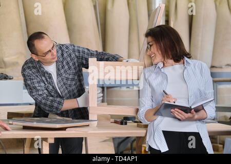 Mobilificio Produzione, lavorazione elemento di giunzione maschio e femmina proprietario di affari con i notebook in officina per la lavorazione del legno Foto Stock