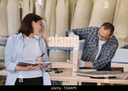 Mobilificio Produzione, lavorazione elemento di giunzione maschio e femmina proprietario di affari con i notebook in officina per la lavorazione del legno Foto Stock