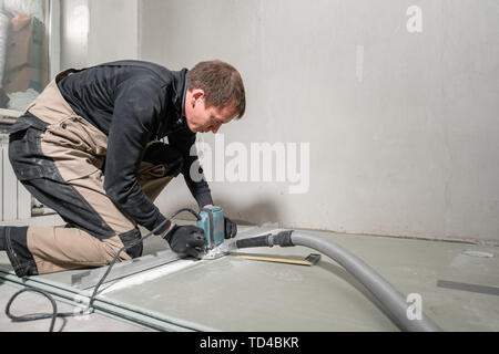 Lavoratore è utilizzando un edificio tool, utensili di fresatura e un aspirapolvere. muro a secco a novanta gradi. Foto Stock