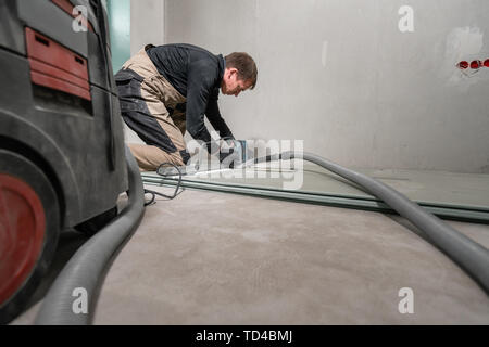 Lavoratore è utilizzando un edificio tool, utensili di fresatura e un aspirapolvere. muro a secco a novanta gradi. Foto Stock