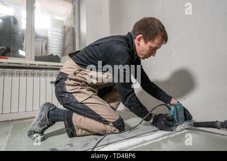 Lavoratore è utilizzando un edificio tool, utensili di fresatura e un aspirapolvere. muro a secco a novanta gradi. Foto Stock