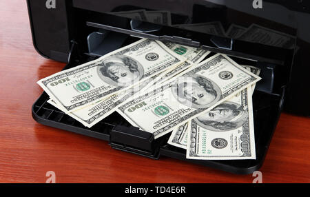 Stampante stampa fake le fatture del dollaro su sfondo di legno Foto Stock