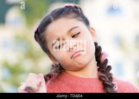 Essa ha bisogno di un buon parrucchiere. Carino bambina guardando lunghi capelli intrecciati. Kids parrucchiere. Parrucchiere per bambini. Facendo i suoi capelli come parrucchiere. Foto Stock