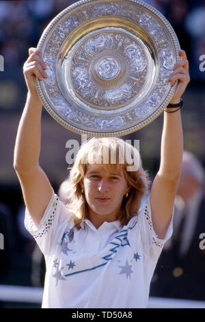 Il torneo di Wimbledon, Grossbritannien. 12 Giugno, 2019. Steffi Graf festeggia il suo cinquantesimo compleanno il 14 giugno 2019, Steffi Graf, Germania, detiene la coppa del vincitore, dopo la sua prima vittoria di Wimbledon, cerimonia di premiazione, guarda verso la telecamera, mezza figura, ritratto, finale Steffi Graf, Germania contro Martina Navratilova, STATI UNITI D'AMERICA, tennis, All England Lawn Tennis e crocket club campionato finale, Ì? Å | Utilizzo di credito in tutto il mondo: dpa/Alamy Live News Foto Stock