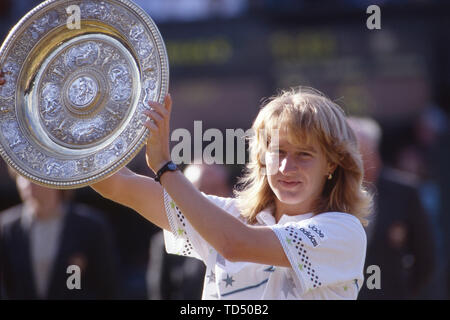 Il torneo di Wimbledon, Grossbritannien. 12 Giugno, 2019. Steffi Graf diventa di cinquanta anni il 14 giugno 2019, Steffi Graf, Germania, trattiene i vincitori' Cup, dopo la sua prima vittoria di Wimbledon, cerimonia di premiazione, guarda verso la telecamera, mezza figura, paesaggio, finale Steffi Graf, Germania contro Martina Navratilova, STATI UNITI D'AMERICA, tennis, All England Lawn Tennis e crocket club campionato finale, Ì? Å | Utilizzo di credito in tutto il mondo: dpa/Alamy Live News Foto Stock