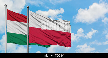 In Ungheria e in Polonia bandiera sventolare nel vento contro bianco torbido cielo blu insieme. Concetto di Diplomazia e relazioni internazionali. Foto Stock