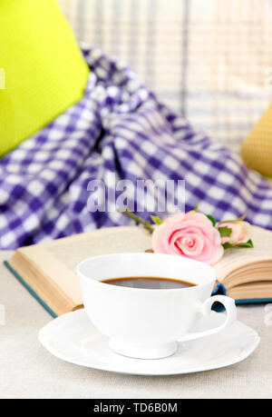 Composizione con tazza di bevanda, libro e fiori su home background interni Foto Stock