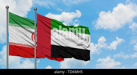 Iran e Emirati Arabi Uniti bandiera sventolare nel vento contro bianco torbido cielo blu insieme. Concetto di Diplomazia e relazioni internazionali. Foto Stock