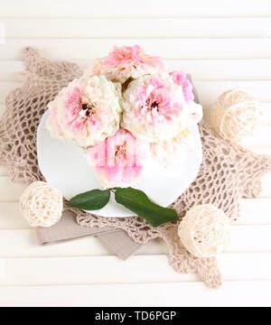 Le Rose in coppa su tovaglioli su sfondo di legno Foto Stock